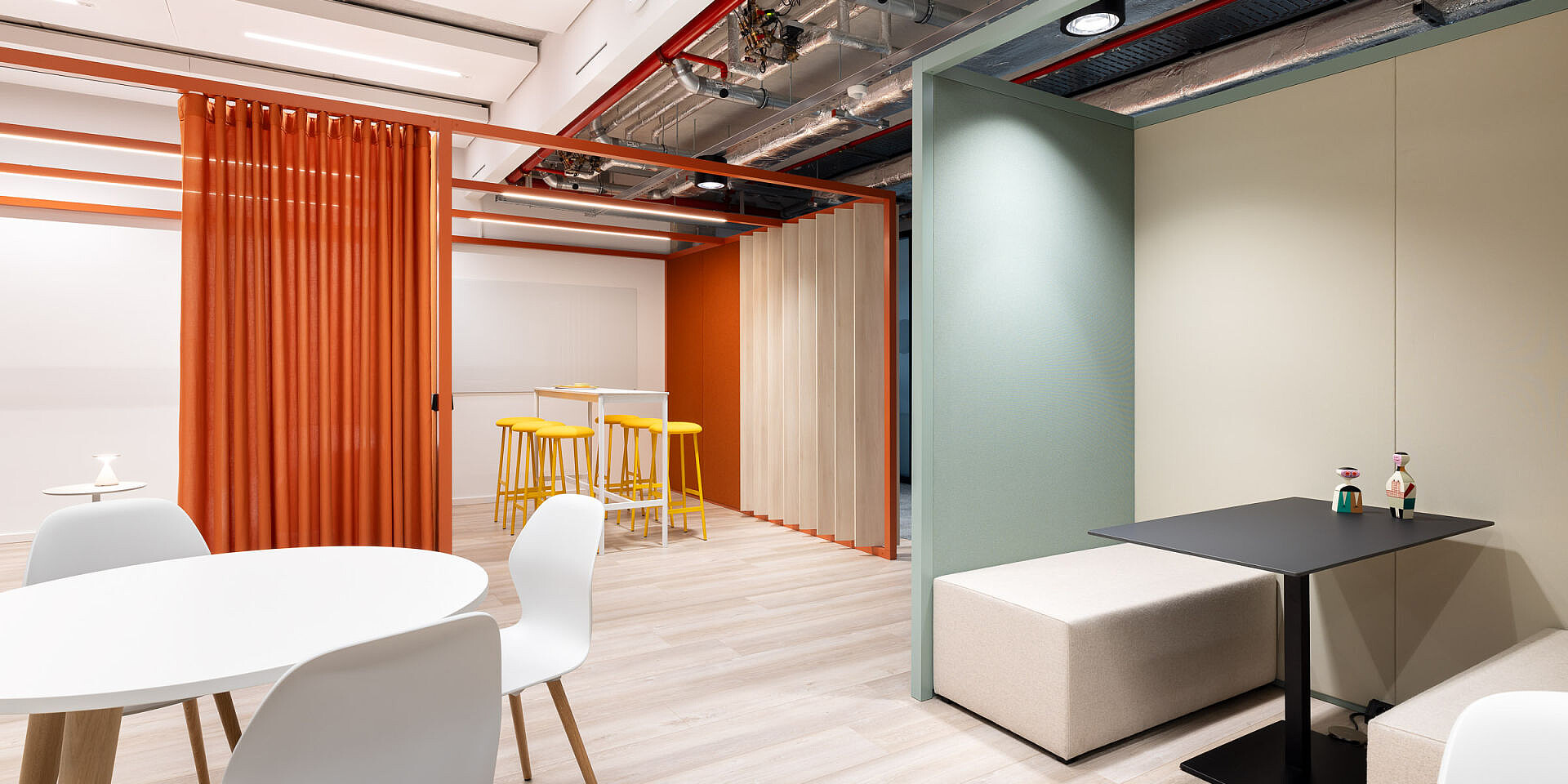 Modern bistro area at Veolia with white se:spot designer chairs and black se:assist tables, surrounded by orange curtains and wooden frames.