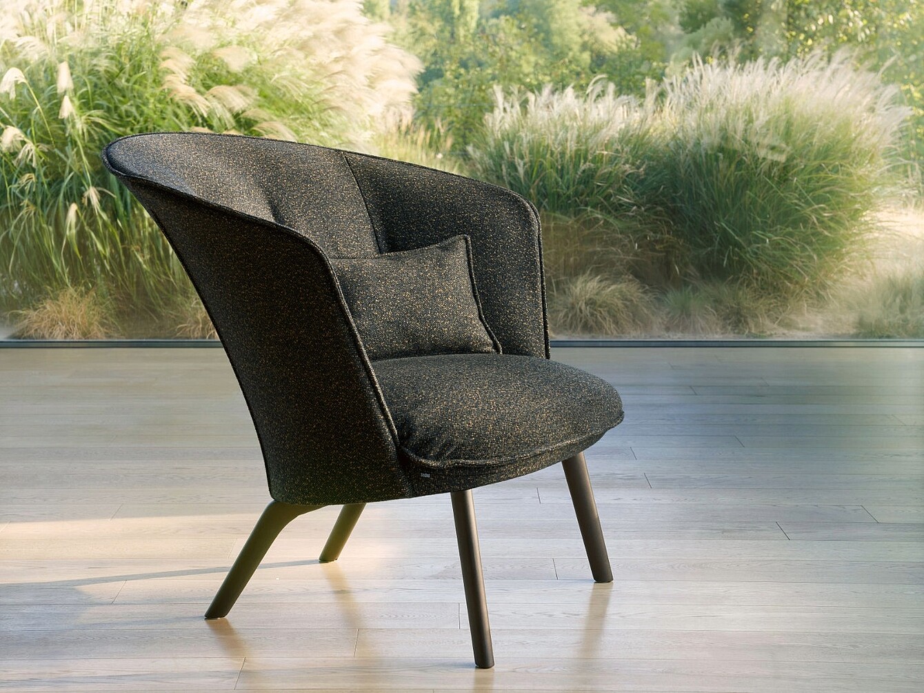 Single modern soft armchair with curved backrest and small cushion on wooden floor in front of window showing outdoor plants