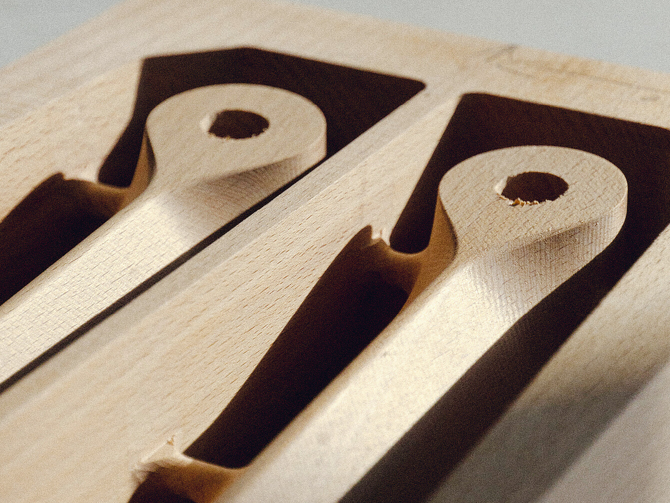 Close-up of two precisely carved wooden chair components for the se:café chair, highlighting smooth craftsmanship and durable material.