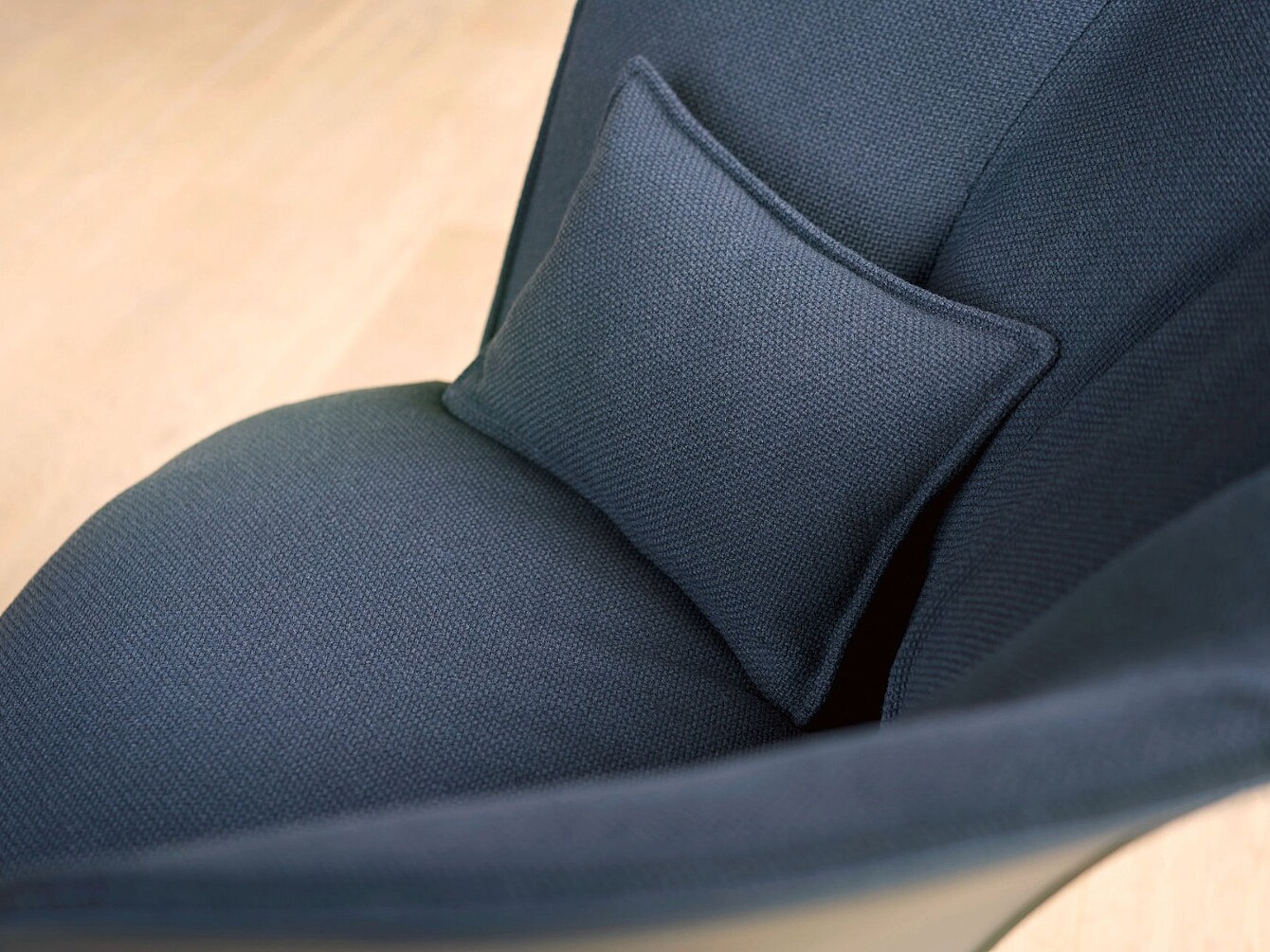 Close-up of a dark fabric armchair with a small matching cushion placed on the seat