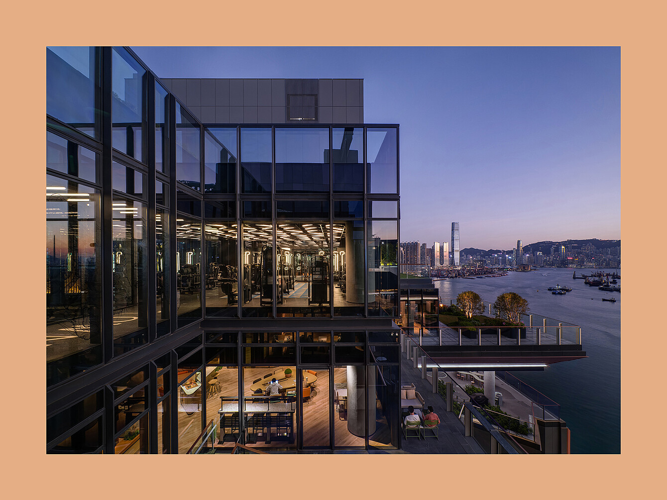 Moderno edificio a più piani con pareti in vetro che si affaccia su un paesaggio urbano sul lungomare al tramonto