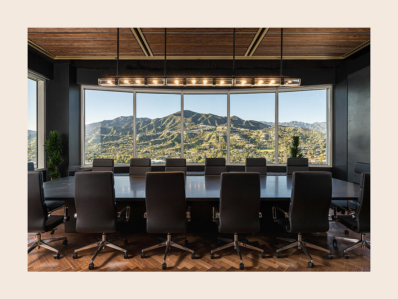 Sala conferenze con un lungo tavolo circondato da sedie da ufficio rivolte verso grandi finestre che mostrano un paesaggio montano